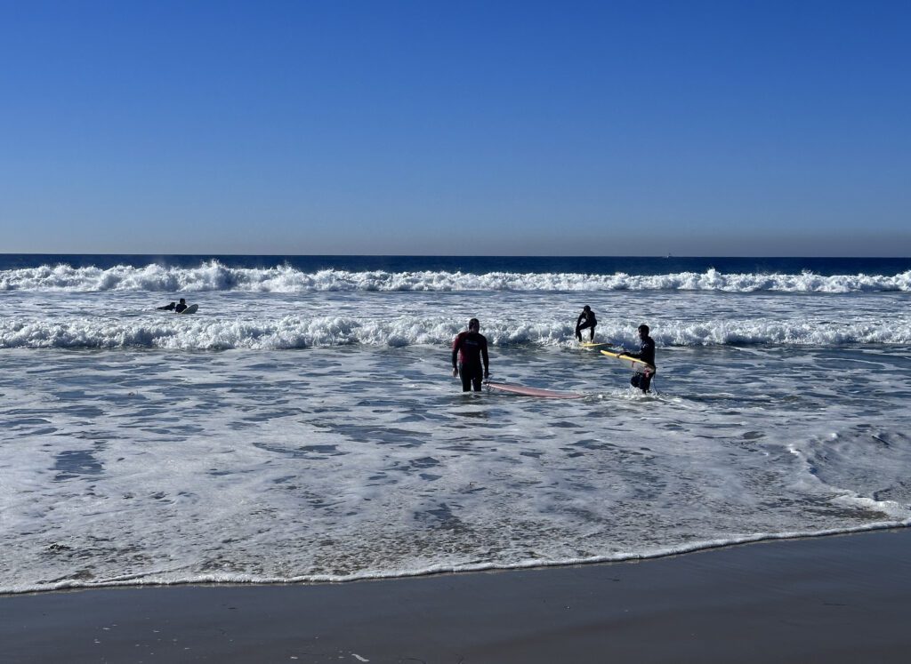 People taking a surfing lesson in Carlsbad beach.